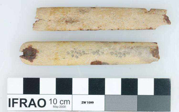 Two rectangles of ivory decorated with small circles, laying one above the other.