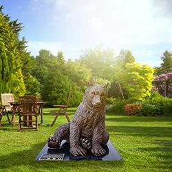 A bronze statue of a baby Marsican brown bear on display in a park