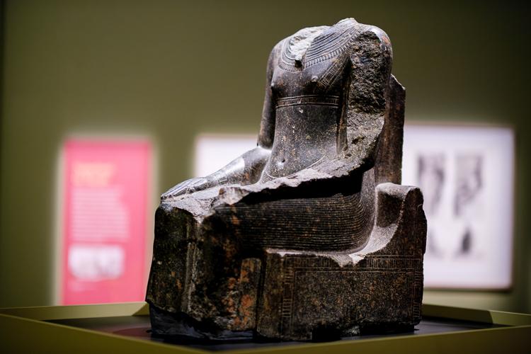 A headless statue, believed to be representative of the Pharaoh Tutankhamun, who is depicted seated with his hands on his knees, carved in a black stone