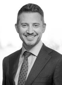 Image of a man in a suit and tie, with short hair.