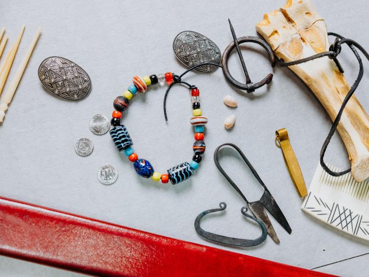 An assortment of replica Viking objects on a touch table included several iron broaches hand beaten coins beaded bracelets shears cloak fasteners and a bone comb