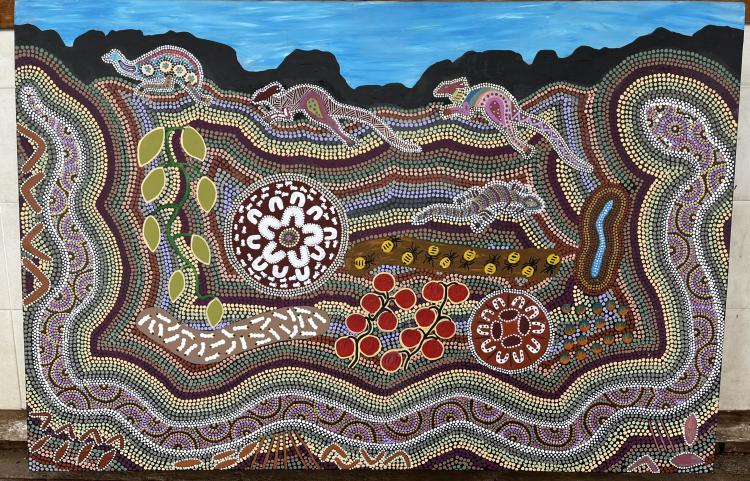 A colourful artwork featuring tight parallel dot painted lines which come toegther to form images of Country, kangaroos, an emu, a lizard and tools and plants of Country