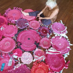Woman sitting on floor surrounded by pink rugs