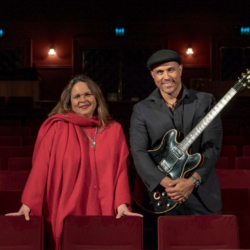 A man and woman smiling for a photo in an auditorium.