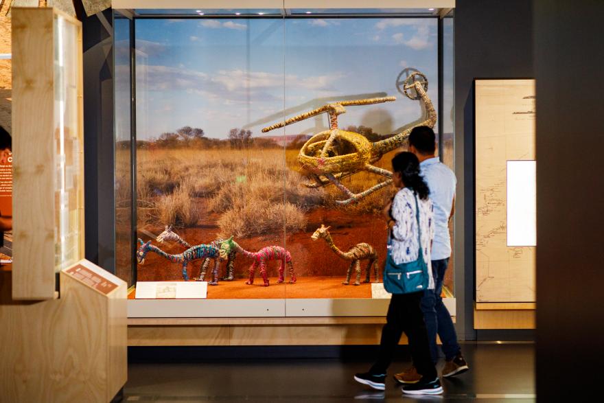 A man and woman observing woven animals in a display.