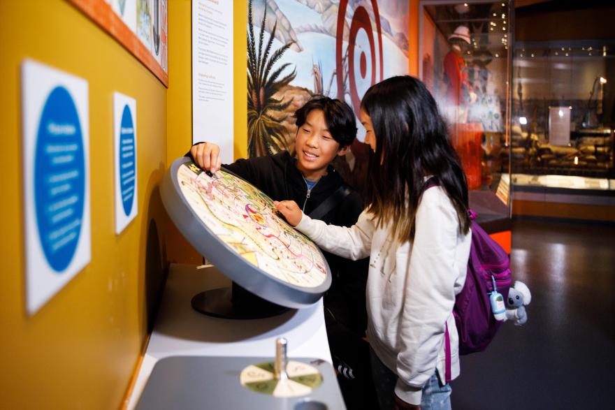 Two children interacting with a round interactive display at a museum.