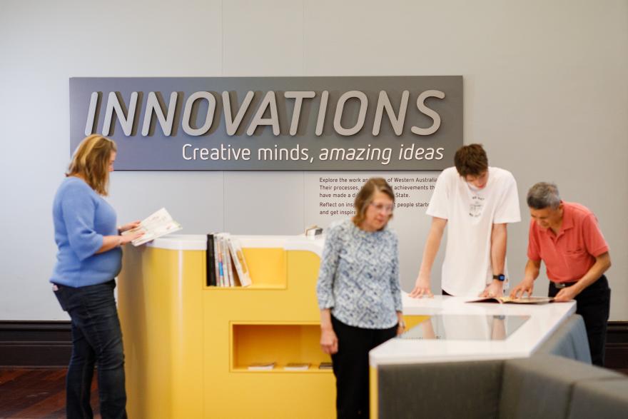 People interacting with exhibits under a sign that reads "INNOVATIONS: Creative minds, amazing ideas."
