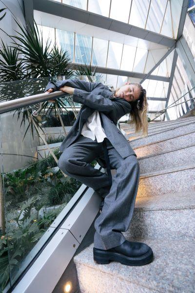 Dancer leans on a stairwell, looking down at the camera