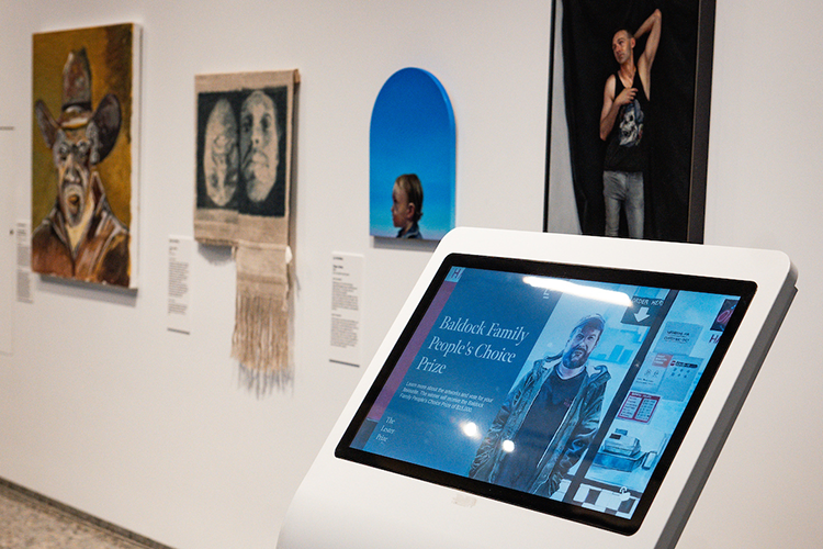 Lester prize portraits on display in gallery with voting kiosk