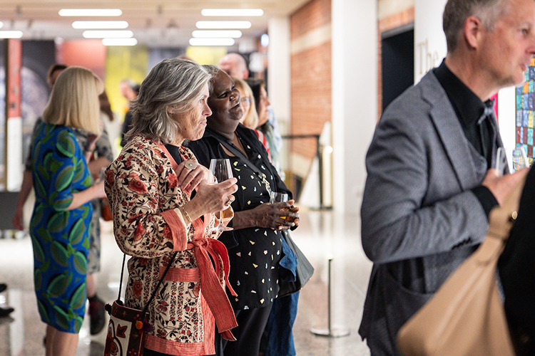 Lester prize portraits on display in gallery observed by visitors