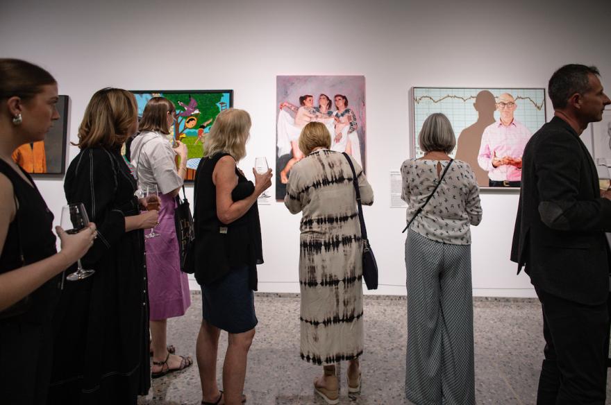 Lester prize portraits on display in gallery observed by visitors