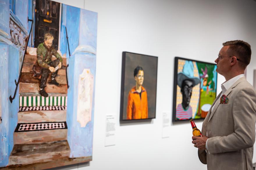 Lester prize portraits on display in gallery observed by visitors