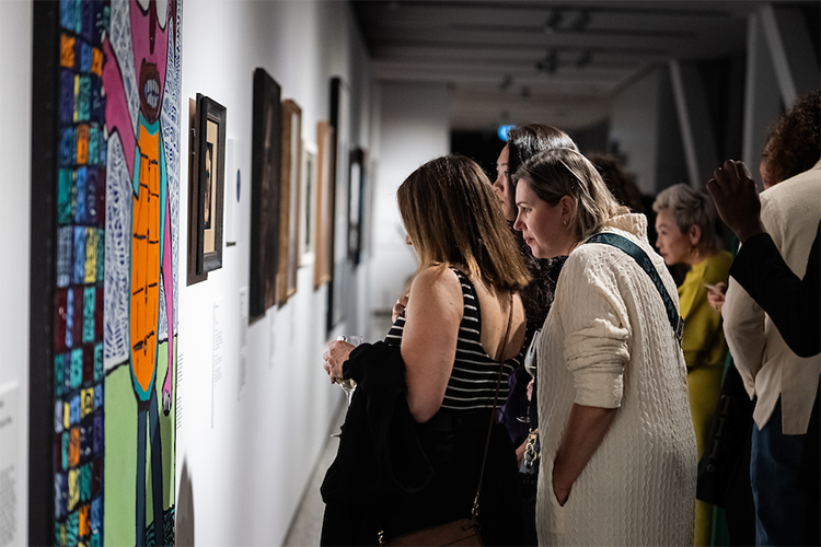 Lester prize portraits on display in gallery observed by visitors