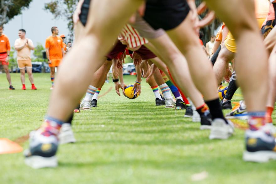 People in a sports formation preparing to play tunnel ball on a grassy field.