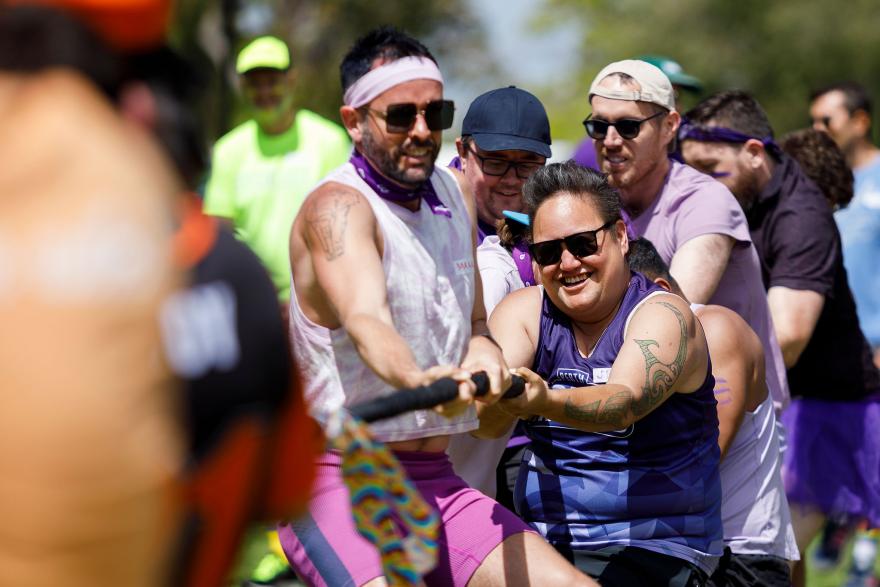 People participating in a tug-of-war outdoors on a sunny day.