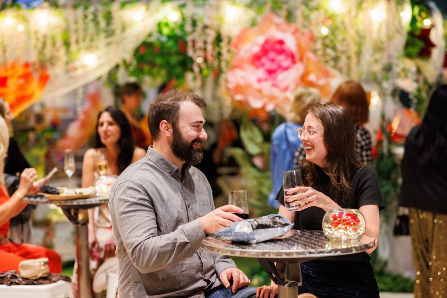 Two people enjoying a conversation at a table in a festive setting with floral decorations.