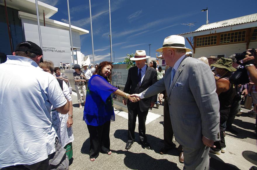 A group of people interact outside the large Maritime Museum building on a sunny day.