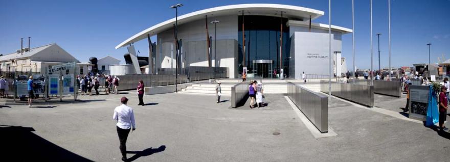 A wide panoramic photo of the entrance to the Western Australian Maritime Museum with people milling around rows of engraved metal panels.