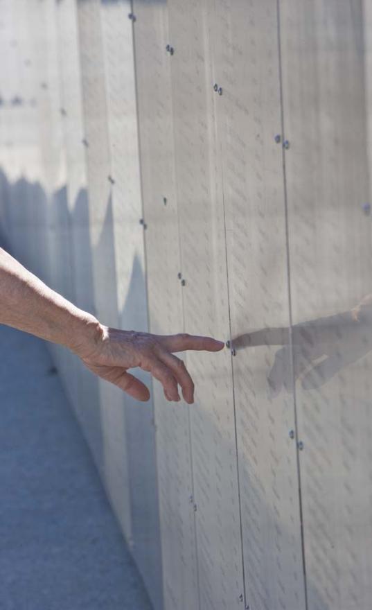 A hand points to a name on an engraved metal panel