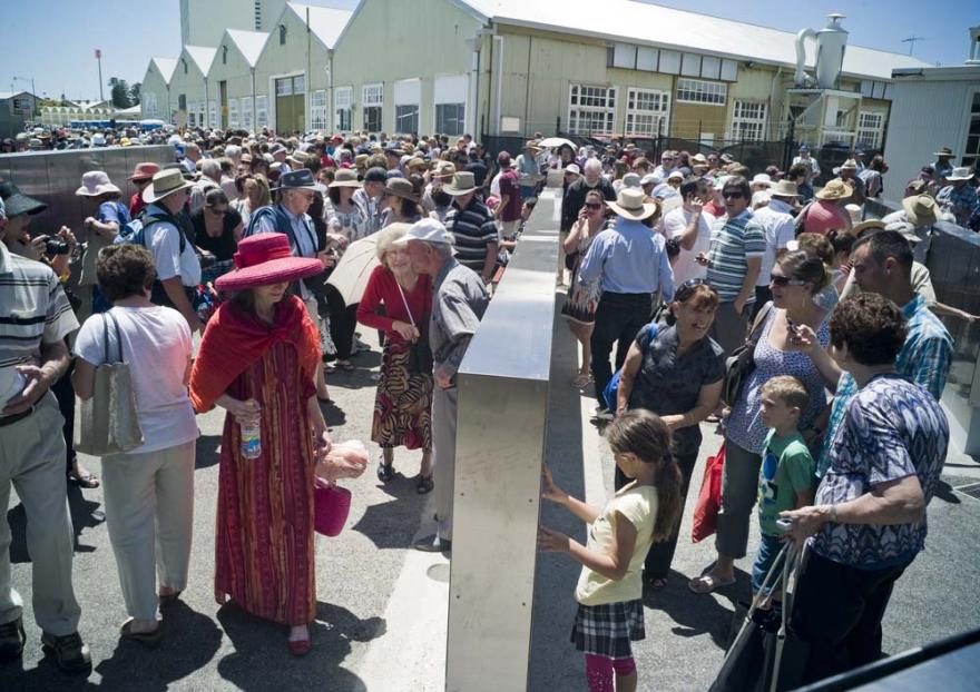 A large group of people wandering around large metal panels engraved with names