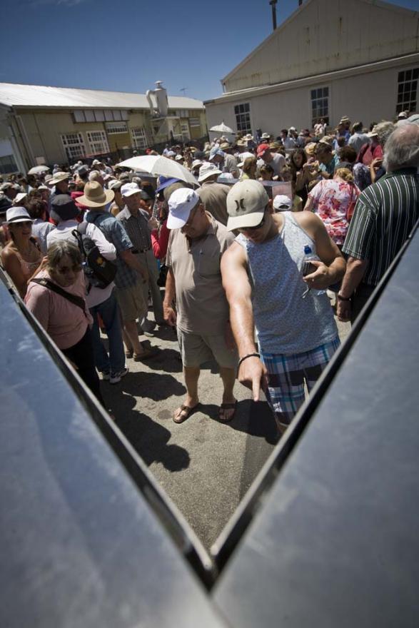A crowd of people examining names on engraved metal panels.