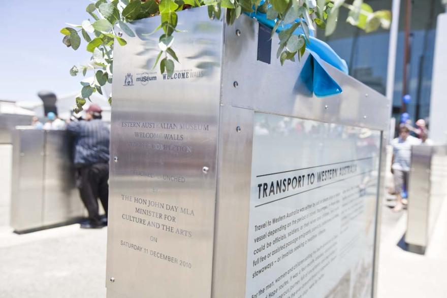 Stainless steel plaque at the Western Australian Museum's Welcome Walls display with green leaves and a blue ribbon.