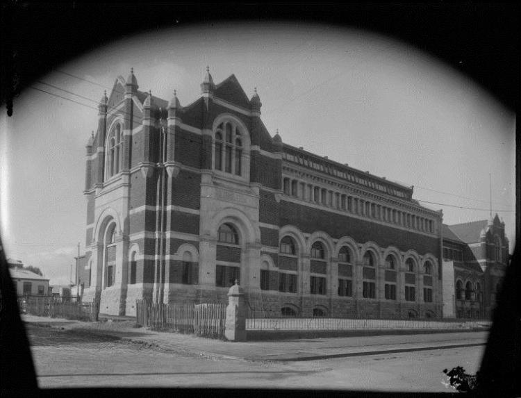 Black and white image of a gothic-style building with arched windows and stone details.