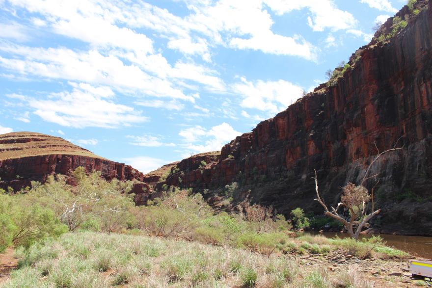 A landscape with large, looming gorges beneath a blue, cloudy sky