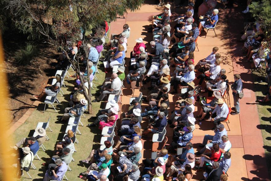 An audience sitting in chairs outdoors