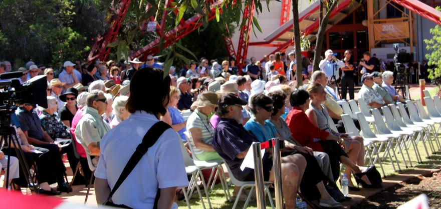 An audience sitting in chairs outdoors