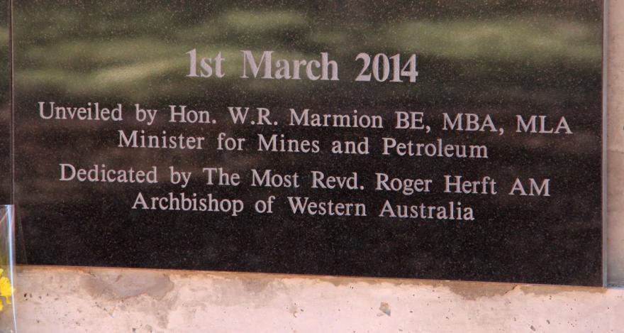 A memorial dedication label that reads '1st March 2014 - Unveiled by Hon. W. R. Marmion BE, MBA, MLA | Minister for Mines and Petroleum | Dedicated by the Most Revd. Roger Herft AM | Archbishop of Western Australia