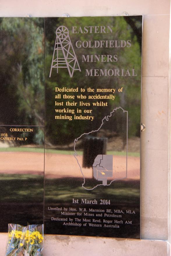 Dedication label that reads 'Eastern Goldfields Miners Memorial | Dedicated to the memory of all those who accidentally lost their lives whilst working in our mining industry.' and 1st March 2014 - Unveiled by Hon. W. R. Marmion BE, MBA, MLA | Minister for Mines and Petroleum | Dedicated by the Most Revd. Roger Herft AM | Archbishop of Western Australia