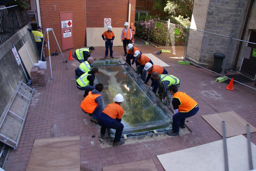 A group of people wearing high-viz lifting the lid of Megamouth's old tank