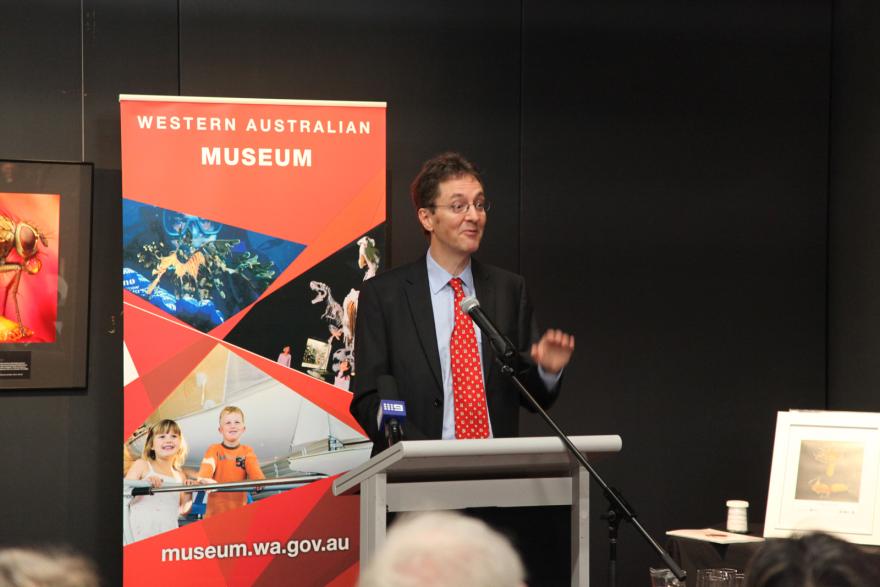 A person speaks at a podium with a Western Australian Museum banner behind him.