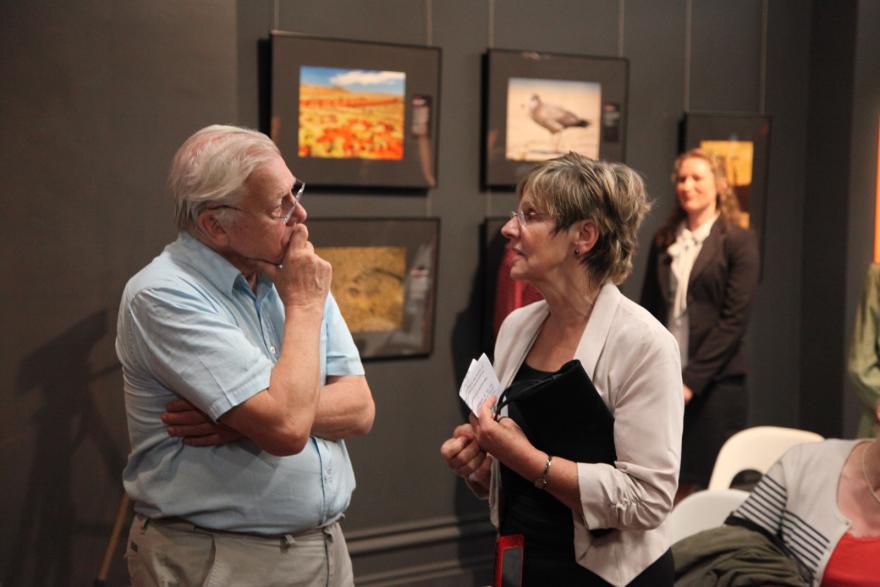 Two people converse in a gallery setting.