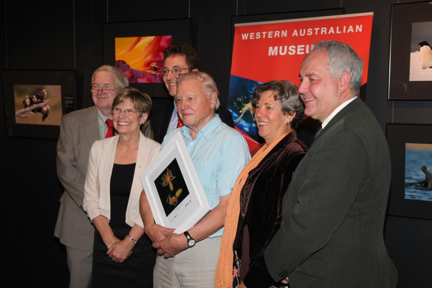 Six people pose in front of a "Western Australian Museum" banner and framed wildlife photos.