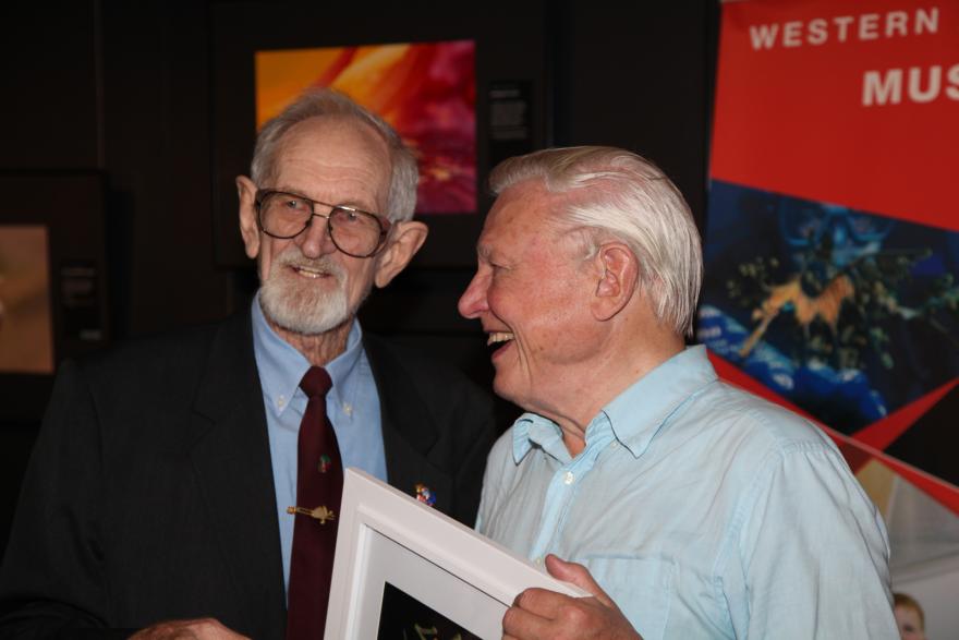 Two people in conversation, one holding a framed picture.