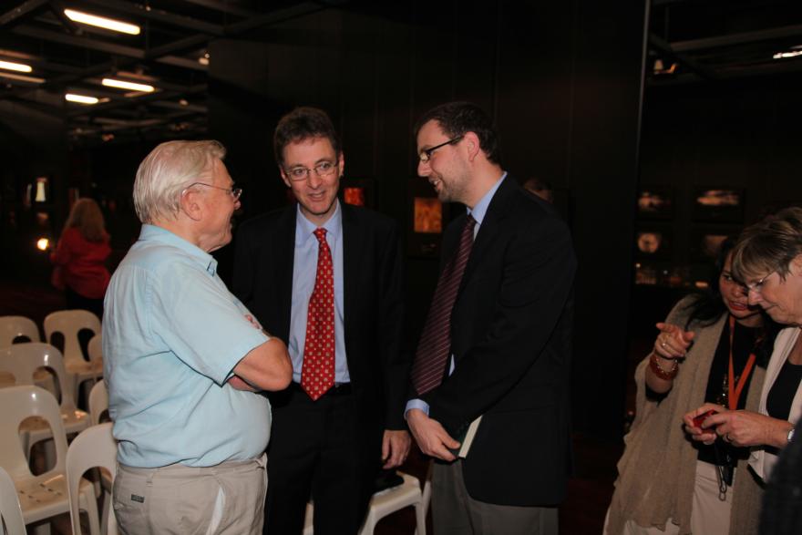 Four people in a room having a conversation, surrounded by empty white chairs.