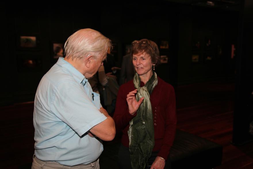 Two individuals conversing in a dimly lit room.
