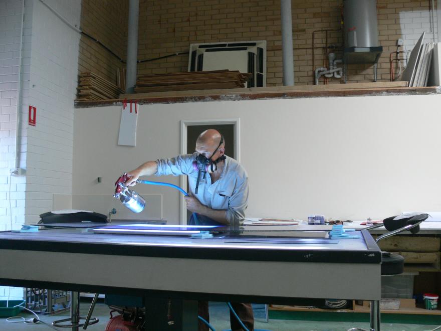 A person wearing a mask works on creating a large glass sculpture