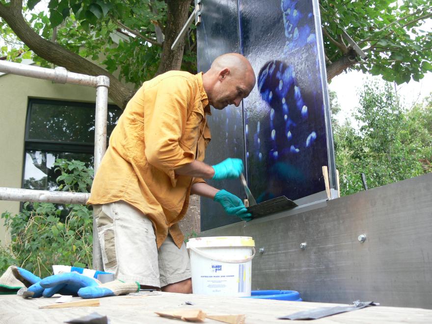 A person building the sculpture "Transparent Sea" in a glass workshop