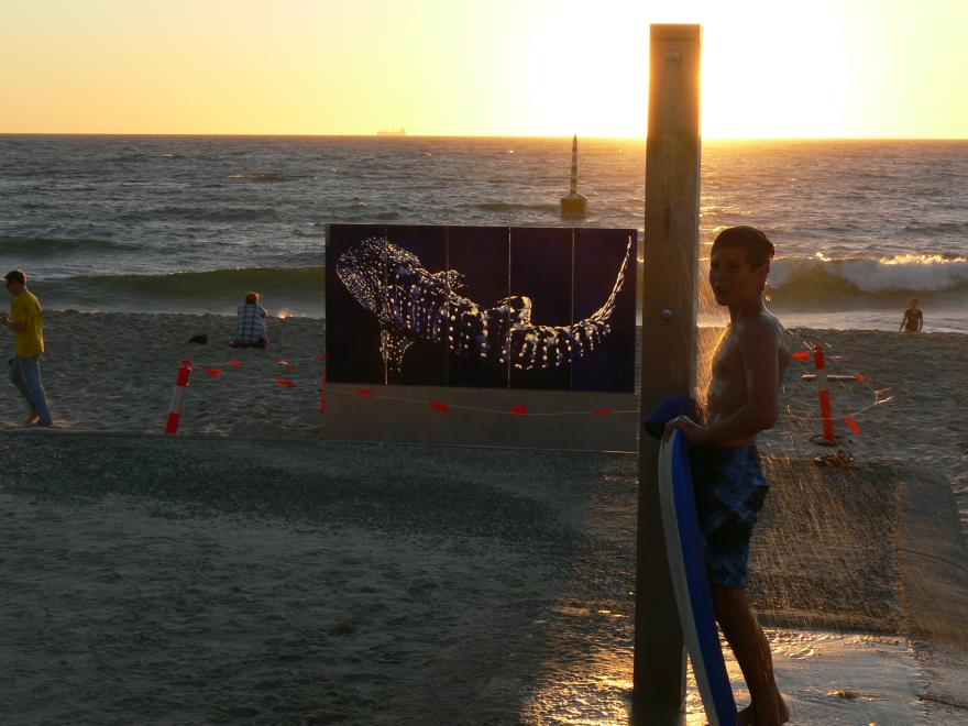 A glass sculpture on display at a beach at sunset