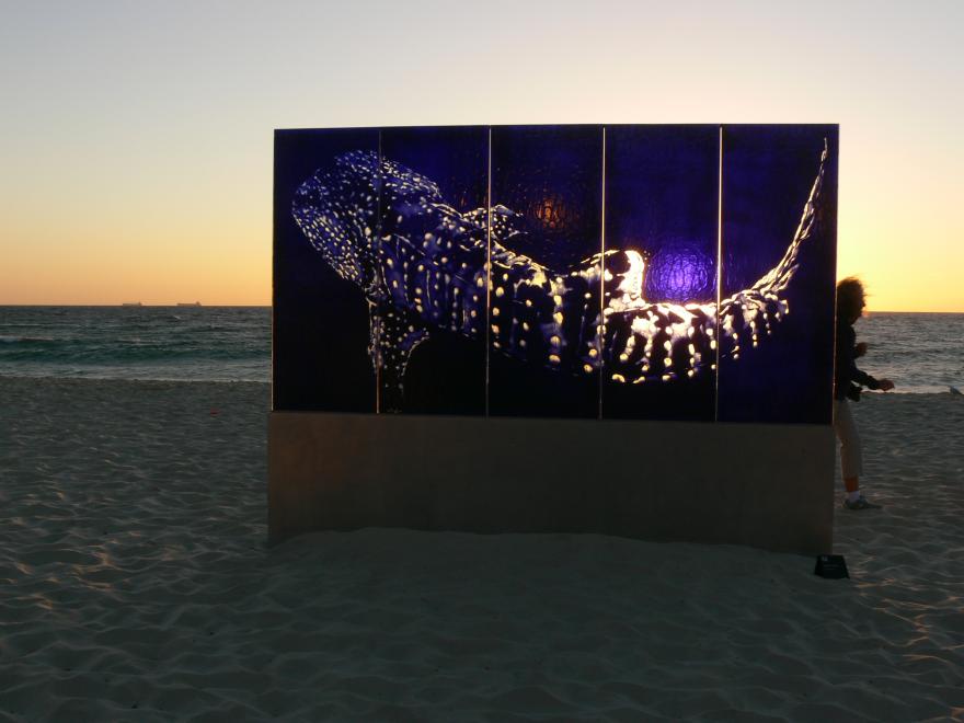 A glass sculpture on display at a beach at sunset