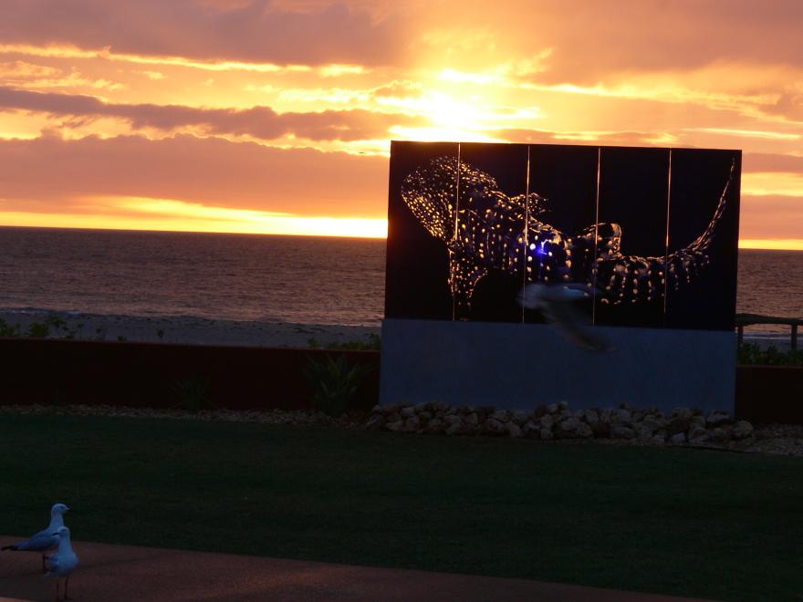 A glass sculpture on display at a beach at sunset