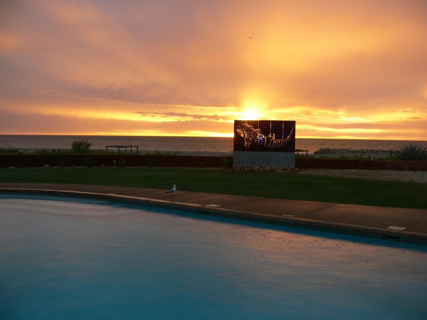 A glass sculpture on display at a beach at sunset