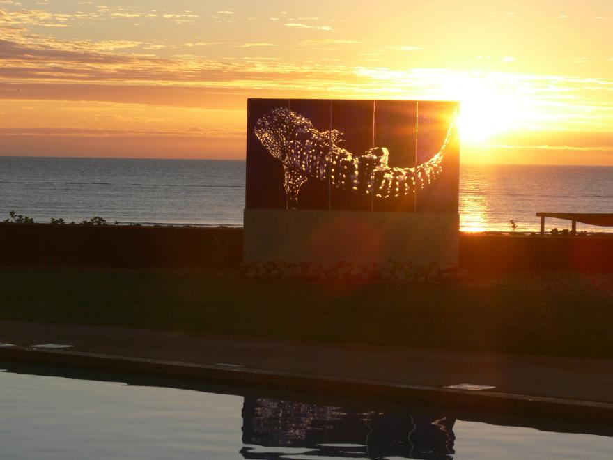 A glass sculpture on display at a beach at sunset