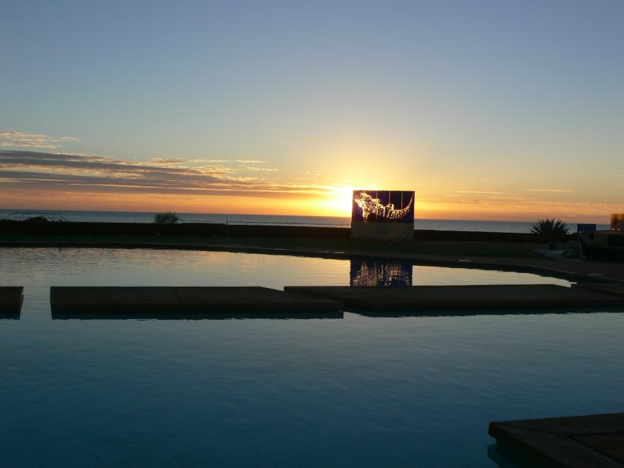 A glass sculpture on display at a beach at sunset