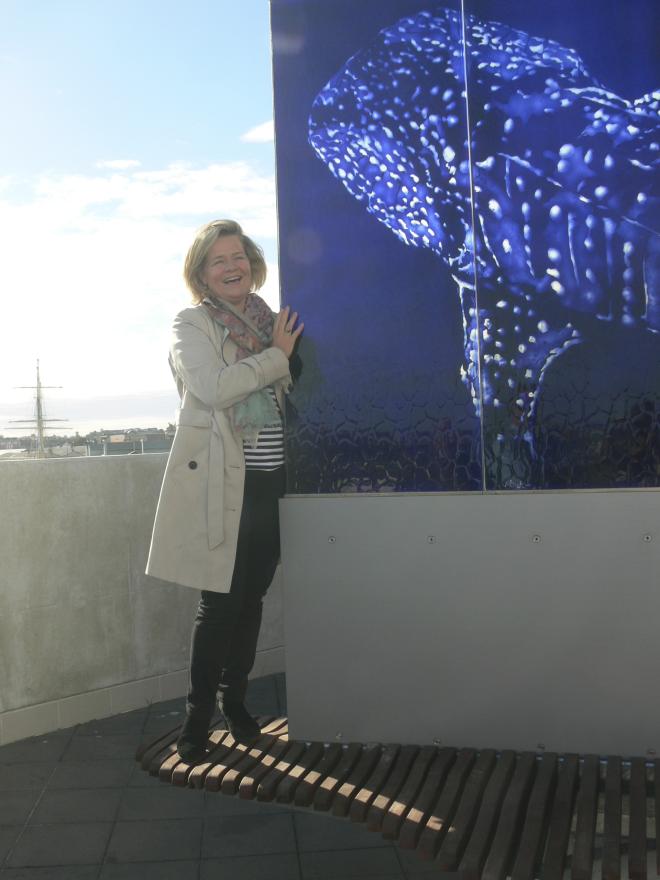 A person standing next to a large glass sculpture of a whale shark