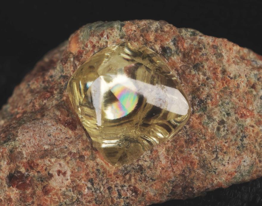 A yellow diamond trapped within a red and brown speckled rock