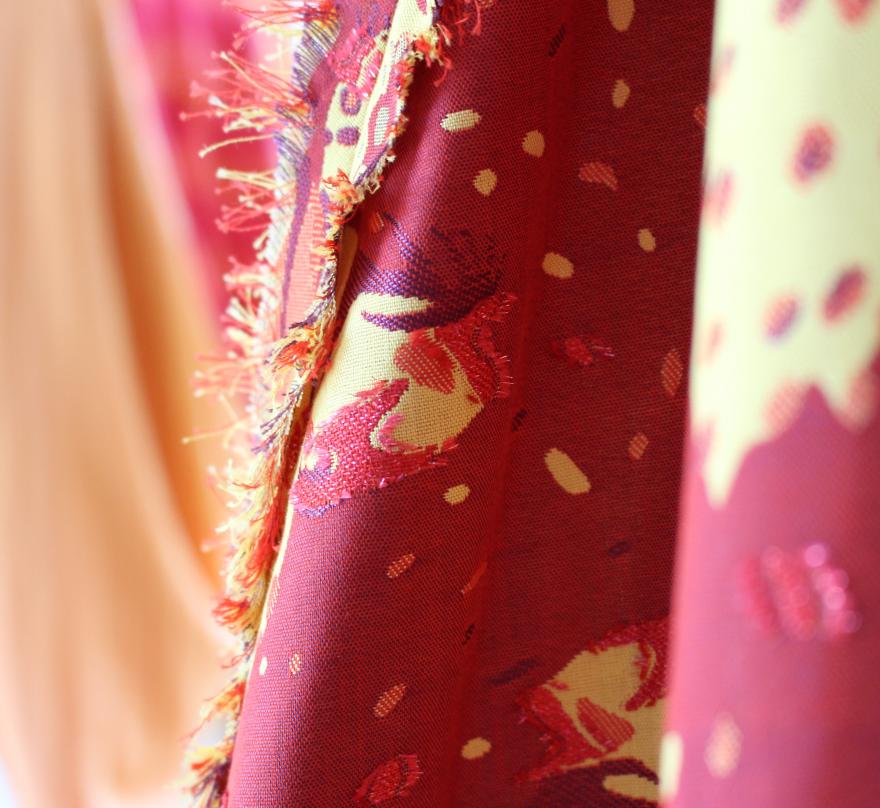  Close-up of a red patterned fabric with frayed edges and yellow accents.